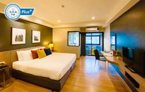 Schlafzimmer mit einem Bett, einem Schreibtisch und einem TV in der Unterkunft Alt Hotel Nana by UHG in Bangkok