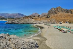 a beach with a bunch of chairs and people in the water at Four Seasons of Bliss at Sohora Hotel in Rethymno