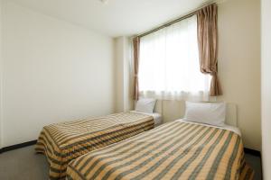 two beds in a small room with a window at コンドミニアム白馬五竜 in Hakuba