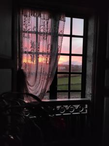 Una donna che guarda fuori da una finestra al tramonto di Casa do Pacio Sabadelle a Lugo