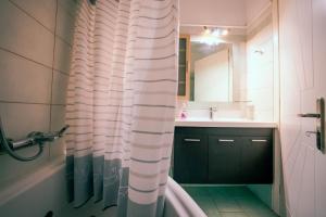 bagno con vasca, lavandino e tenda per la doccia di Beautiful house in Aegina a Città di Egina