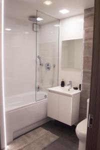 a white bathroom with a shower and a sink at Siauliai Apartments - Lieporiu in Šiauliai