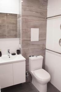a white bathroom with a toilet and a sink at Siauliai Apartments - Lieporiu in Šiauliai