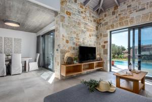 salon z kamienną ścianą i telewizorem w obiekcie Villa Angelos w mieście Kateleios