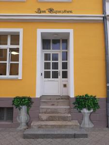 a yellow house with a white door and stairs at Ferienwohnung Zum Rapunzelturm in Schwedt