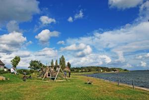 um parque com um parque infantil ao lado de um corpo de água em Ferienwohnung Moewennest mit Terra em Middelhagen
