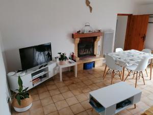 un soggiorno con tavolo, TV e camino di Chez pépé a Barbâtre
