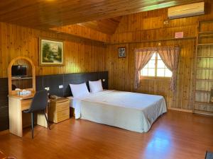 een slaapkamer met een bed, een bureau en een raam bij Da Fang Hua Yuan Xiao Homestay in Fenglin