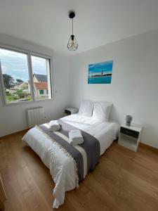 a white bedroom with a bed and two windows at Bel appartement à 200m de la plage in Barneville-Carteret