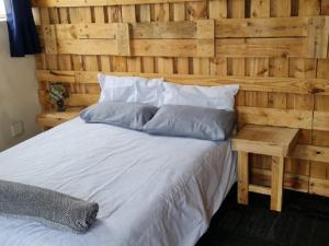 een slaapkamer met een houten muur en een bed bij Sunset beach backpackers in Bloubergstrand +44 foto's
