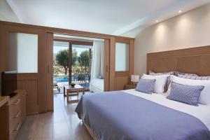 a bedroom with a bed and a television and a patio at Atlantica Aegean Park in Kolimbia