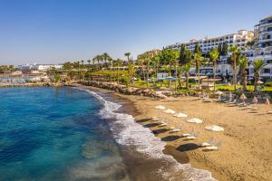 a beach with chaise lounges and a resort at Coral Beach Hotel & Resort Cyprus in Coral Bay
