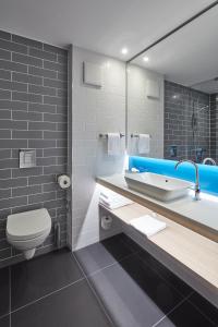 a bathroom with a toilet and a sink and a mirror at Holiday Inn Express - Merzig, an IHG Hotel in Merzig