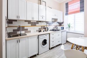 リヴィウにあるOld Town Cosy Apartmentの白いキャビネットと食器洗い機付きのキッチンが備わります。