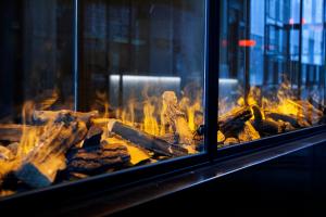 a pile of wood is burning in a fireplace at Next House Copenhagen in Copenhagen