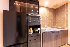 uma cozinha com um frigorífico preto e um lavatório em スタジオーネ 箱根強羅 East - Stagione Hakone Gora East em Hakone