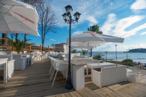 a patio with tables and umbrellas on the beach at Hermes Club Hotel - Ultra All Inclusive in Tsarevo