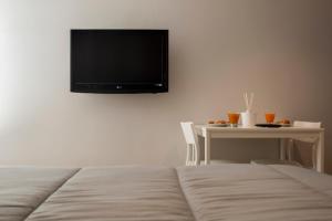 ein Schlafzimmer mit einem Bett und einem Tisch mit einem TV an der Wand in der Unterkunft Dea Casa Vacanze in Salerno