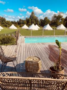 um deque de madeira com uma piscina, cadeiras e tendas em GreenValleyGlamping em Šešče pri Preboldu