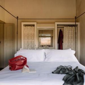 una bolsa roja sentada encima de una cama blanca en Tenuta di Fessina, en Castiglione di Sicilia