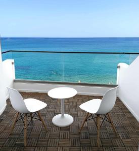 2 stoelen en 2 tafels op een balkon met uitzicht op de oceaan bij Azure Mare Hotel in Chersonissos