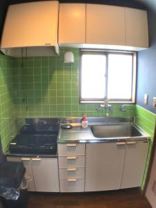 cocina con azulejos verdes, fregadero y ventana en YADO OMIYA / Vacation STAY 45672, en Kamogawa