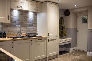 una cucina con mobili bianchi e un lavandino di Beckside a West Burton Altre 34 foto