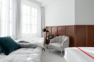 a bedroom with a row of beds and a chair at Ruby Mimi Hotel Zurich in Zürich