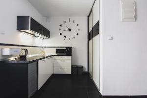 una cocina con armarios blancos y un reloj en la pared en Apartament Górski - SPA pod Nosalem, en Zakopane