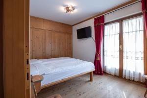 a bedroom with a bed and a tv and windows at Casa Belvedere 1 in San Vito di Cadore