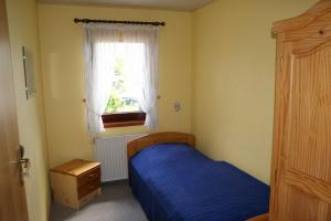 Un dormitorio con una cama azul y una ventana. en Dat hyggelige Ferienhus in Kappeln, en Kappeln
