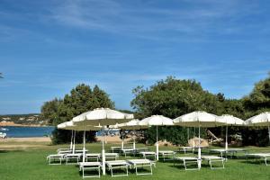 Ein Haufen weißer Stühle und Sonnenschirme am Strand in der Unterkunft Bagaglino I Giardini Di Porto Cervo in Porto Cervo