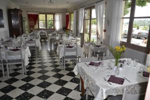 un ristorante con tavoli e sedie bianchi e finestre di Hotellerie de l'Esplanade a Rians