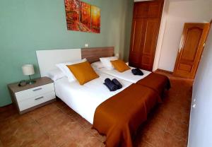 1 dormitorio con 1 cama blanca grande con almohadas de color naranja en EL CHALET, en Rascafría
