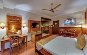 a bedroom with a large bed and a desk and a chair at JC Residency Madurai in Madurai
