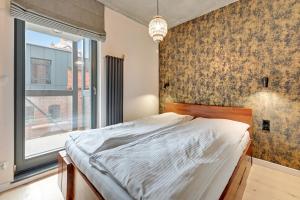 a bedroom with a bed and a large window at Grand Apartments - Browar Gdański - Design Apartment in Gdańsk