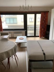 a room with a bed and a table and some windows at Zongerichte studio Sint-Idesbald met mooi zeezicht in Koksijde