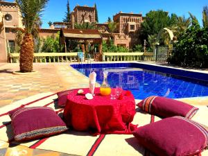 a table with a drink on it next to a pool at Kasbah Tiriguioute in Skoura