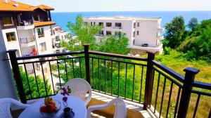 een balkon met een tafel en stoelen en de oceaan bij Бяла Виста Бийч Апартментс B - Byala Vista Beach Apartments B in Byala