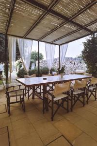 un grande tavolo in legno con sedie sotto un pergolato di Don Agostino Relais Masseria a Martano