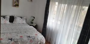 a bedroom with a bed and a window with white curtains at Vila Curtea de Arges in Curtea de Argeş