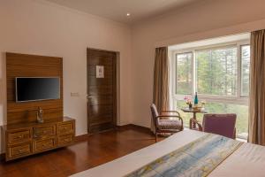 a bedroom with a bed and a tv and a window at StayVista at Albert Estate in Mussoorie