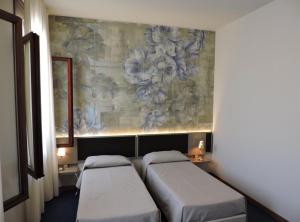 two beds in a room with a painting on the wall at Albergo Leon D'Oro in Maniago