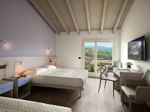 sypialnia z 2 łóżkami, biurkiem i oknem w obiekcie Residence Caffè Maya w mieście Maslianico