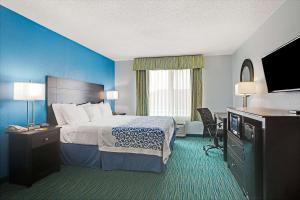 a hotel room with a bed and a flat screen tv at Days Inn by Wyndham Dallas Garland West in Garland