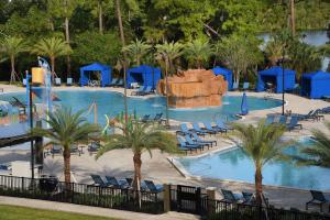 a large swimming pool with palm trees and blue umbrellas at Wyndham Lake Buena Vista Resort Disney Springs® Resort Area in Orlando