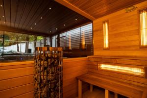 a wooden sauna with a bench and a fireplace at Arena Deluxe & Spa in Szeged