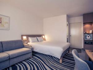 a hotel room with a large bed and a couch at Novotel Bourges in Bourges