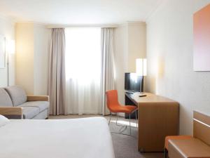 a hotel room with a bed and a desk at Novotel Paris Pont De Sevres in Sèvres