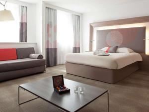 ein Hotelzimmer mit einem Bett und einem Sofa in der Unterkunft Novotel Paris Pont De Sevres in Sèvres